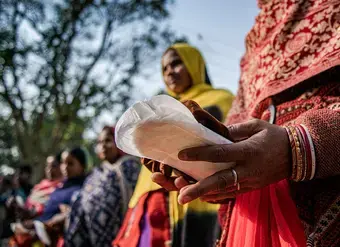 In Sitamarhi State, Bihar, India, in 2022, women hold sanitary pads during an awareness campaign as part of a menstrual hygiene management program organized by UNICEF.