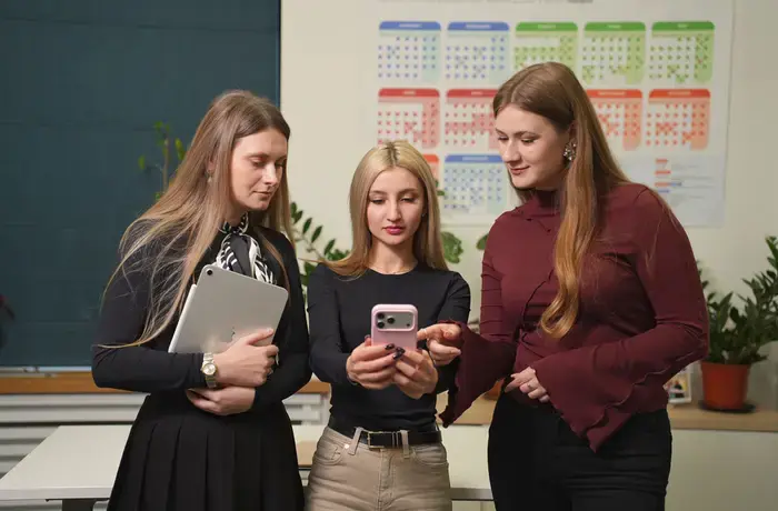 Three young women look at a phone