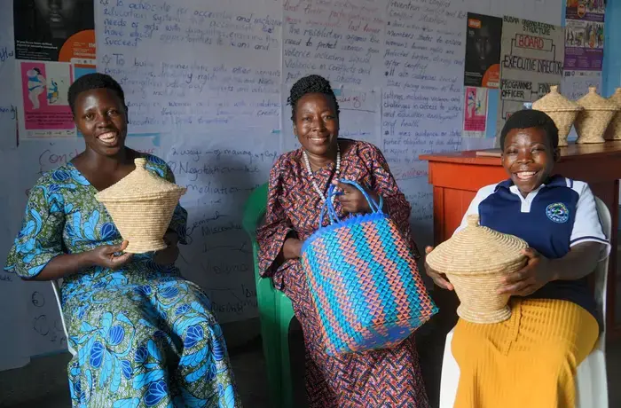 Three women display their handmade baskets